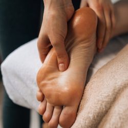 Hands massaging a foot to provide relaxation and promote wellness indoors.